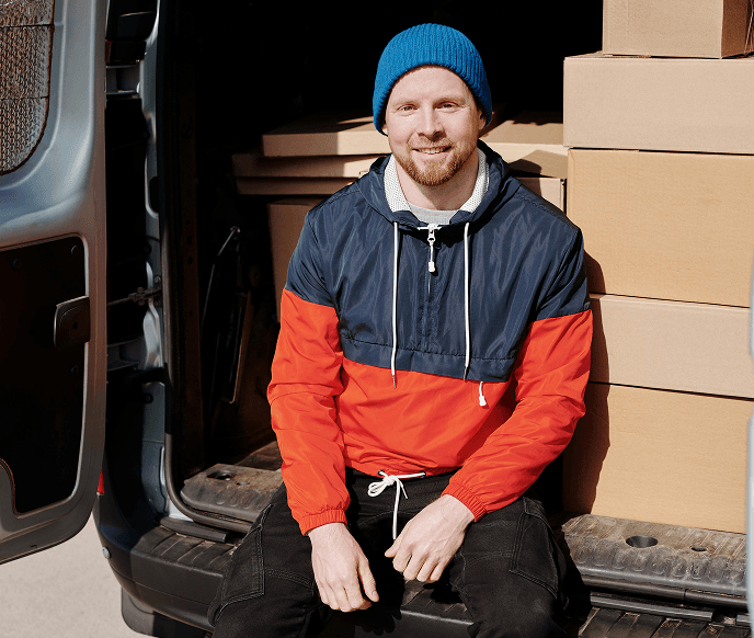 A man sitting at the trunk of a delivery car